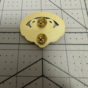 Reverse of a gold-plated enamel pin showing two butterfly clutches